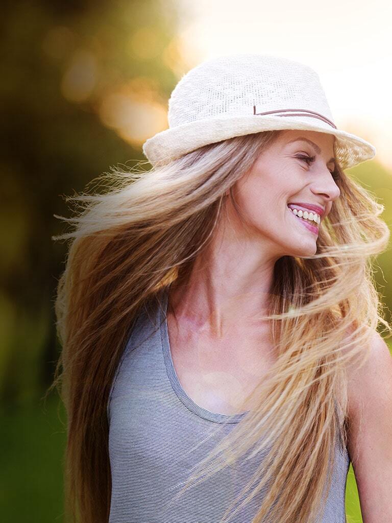Woman in a gray tank top with straw hat, smiling